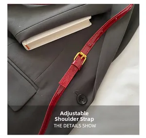 Detail of red patent leather shoulder strap with golden buckle and adjustable holes