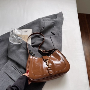 Sac hobo marron vintage en cuir verni avec boucle en métal doré sur veste grise