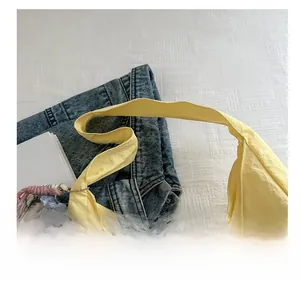 Detail of light yellow textured tote bag with wide strap and cute plush charm