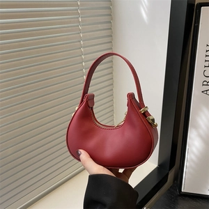 French luxury red half-moon handbag with gold hardware shown in a minimalist setting