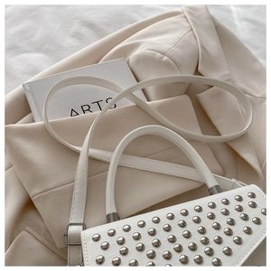Detail of white studded handbag with silver rivets on flap and adjustable strap