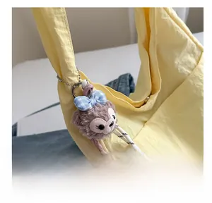 Detail of cute purple bunny plush pendant with blue plaid bow on yellow tote bag