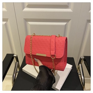 Detail of coral pink woven texture handbag with golden chain strap and metal clasp