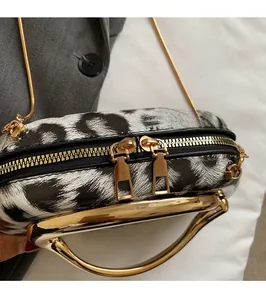 Close-up of leopard print acrylic clutch featuring gold ring handles and dual metal zippers