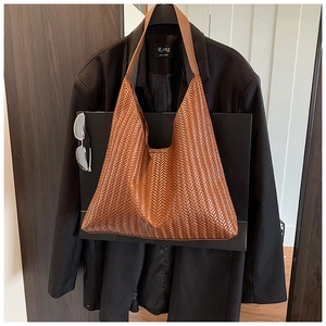 Close-up of brown woven texture on large shoulder bag hung on black suit jacket