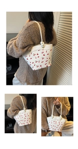 Detail of white bucket bag with cherry print and decorative knotted rope shoulder strap