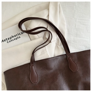 Dettaglio ravvicinato della borsa tote in pelle marrone scuro con eleganti tracolle lunghe