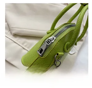 Macro view showing smooth silver zipper and textured lychee pattern on green shell bag