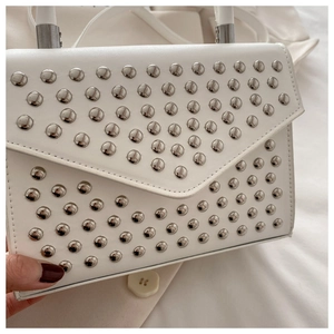 Detail of white leather handbag with silver stud embellishments and V-flap closure