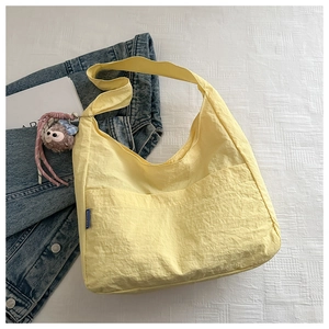 Detail of light yellow nylon tote bag with fashion label and cute plush monkey charm