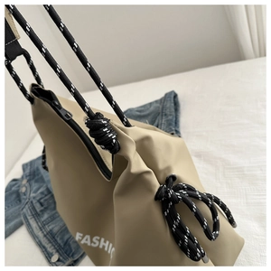 Détail du sac kaki avec bandoulière corde, lettrage et nœud sur une veste en jean