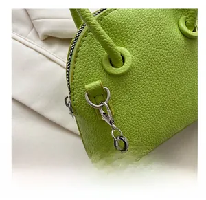 Detail of bright green litchi texture leather bag with silver metal chain and D-ring