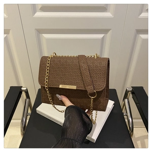 Close-up of brown woven texture and gold chain on the minimalist shoulder bag
