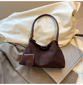 Detailed view of dark brown suede shoulder bag with textured pleats and leather handle