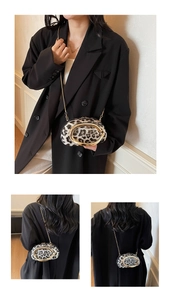 Detail of animal print texture with a chunky gold C-buckle and metal chain strap