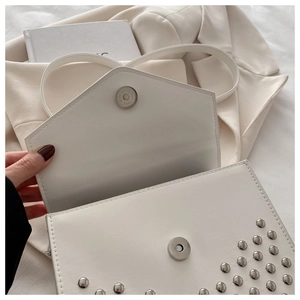 Detail of white PU leather handbag with silver rivets and magnetic snap closure