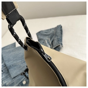 Détail du sac cabas en nylon kaki avec fermeture éclair noire et bandoulière en corde rayée