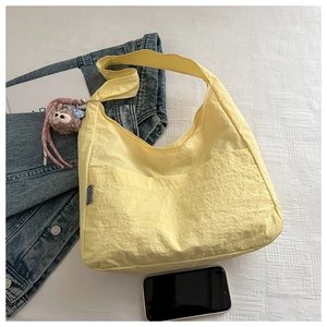 Flat lay of a yellow casual tote bag with plush charm, denim jacket and magazines