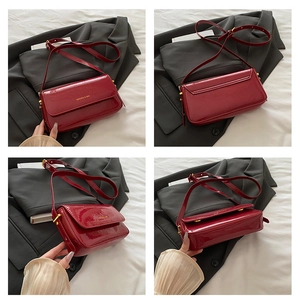 Detail view of burgundy patent leather square crossbody bag with gold metal buckle