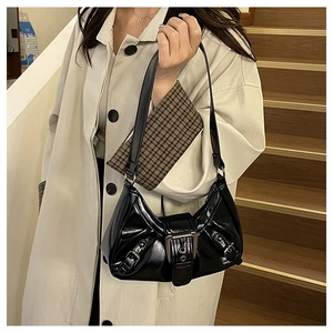 Detail of glossy black shoulder bag with vintage metal buckles and retro patent leather