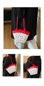 Detail view of cherry print tote bag with red contrast straps and PU leather texture