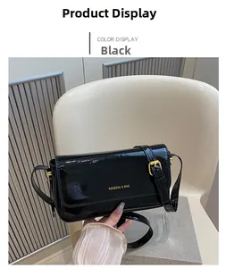 Detailed view of black patent leather square crossbody bag with gold buckle and logo