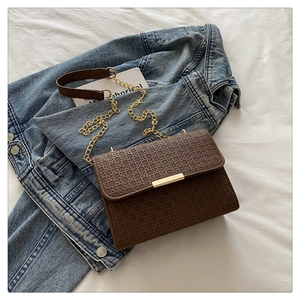 Close-up of brown woven texture on shoulder bag with elegant gold chain strap