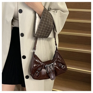 Chocolate glossy faux leather shoulder bag with large metal buckle detail on a model