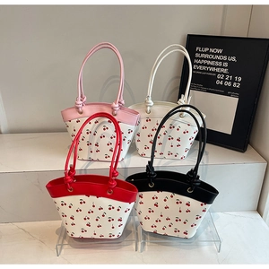 Detail view of four cherry-printed tote bags with assorted pink, black, and red handles
