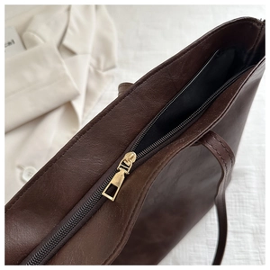 Dettaglio della borsa tote vintage in pelle marrone con chiusura lampo dorata in alto