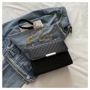 Close-up of woven flap texture and gold metal chain strap on a black luxury crossbody bag