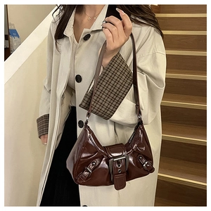 Detail of dark brown patent leather shoulder bag with vintage buckles and glossy finish