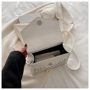 Close-up of white rectangular handbag showing silver rivet details and internal capacity