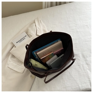 Interno spazioso della borsa tote marrone scuro con tablet, libri e oggetti vari