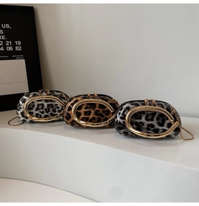 Detail showing leopard print texture and bold gold C-shaped metal buckle on the chain bag