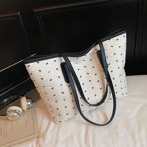 Chic cream tote bag with black bow pattern and slim shoulder straps for daily office use