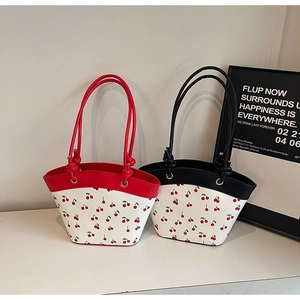 Detailed view of red and black cherry print tote bags with knotted leather straps