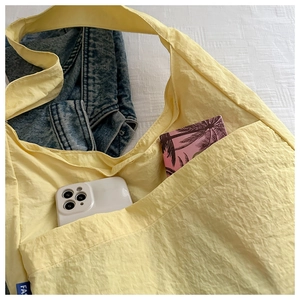 Detail of the light yellow tote bag with washed texture fabric and blue side label