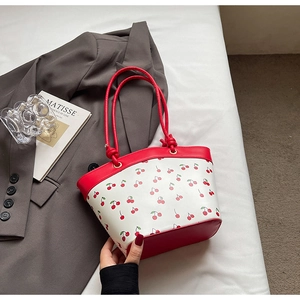 Detail of cherry print tote bag with red trim and rope handles on a lifestyle background