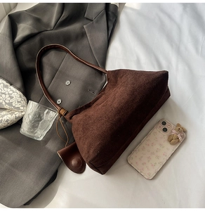 Detail of dark brown suede shoulder bag with leather strap and decorative pendant