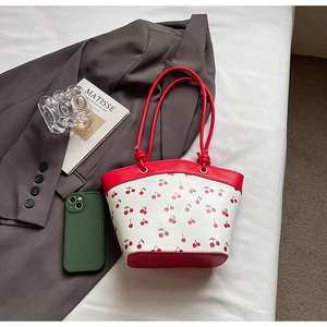 Detail view of contrast cherry print shoulder bag with red trim and slender handles