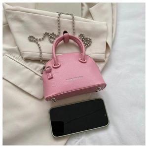 Pink mini lychee leather shell bag with silver chain strap shown next to a smartphone