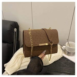 Close-up of brown woven texture handbag with gold chain strap and metal clasp detail
