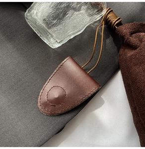 Detail view of brown leather key case with precise hand-stitched edges and fine suede cord