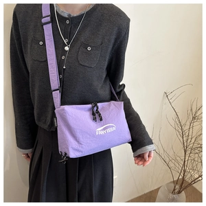 Détail du sac bandoulière en nylon violet avec logo tissé et sangle noire ajustable