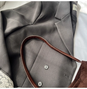 Detailed view of dark grey twill suit jacket texture with branded neck label and buttons