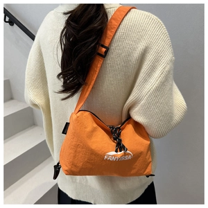 Détail d'un sac bandoulière en nylon orange avec sangle réglable et fermeture éclair
