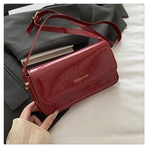 Close-up of red patent leather shoulder bag with gold hardware and logo on blazer