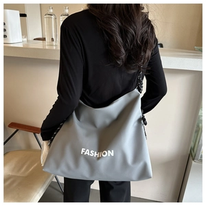 Detail of grey waterproof nylon crossbody bag with large white FASHION lettering