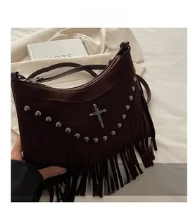 Detail of suede crossbody bag with metal cross, skull emblem and long fringe accents